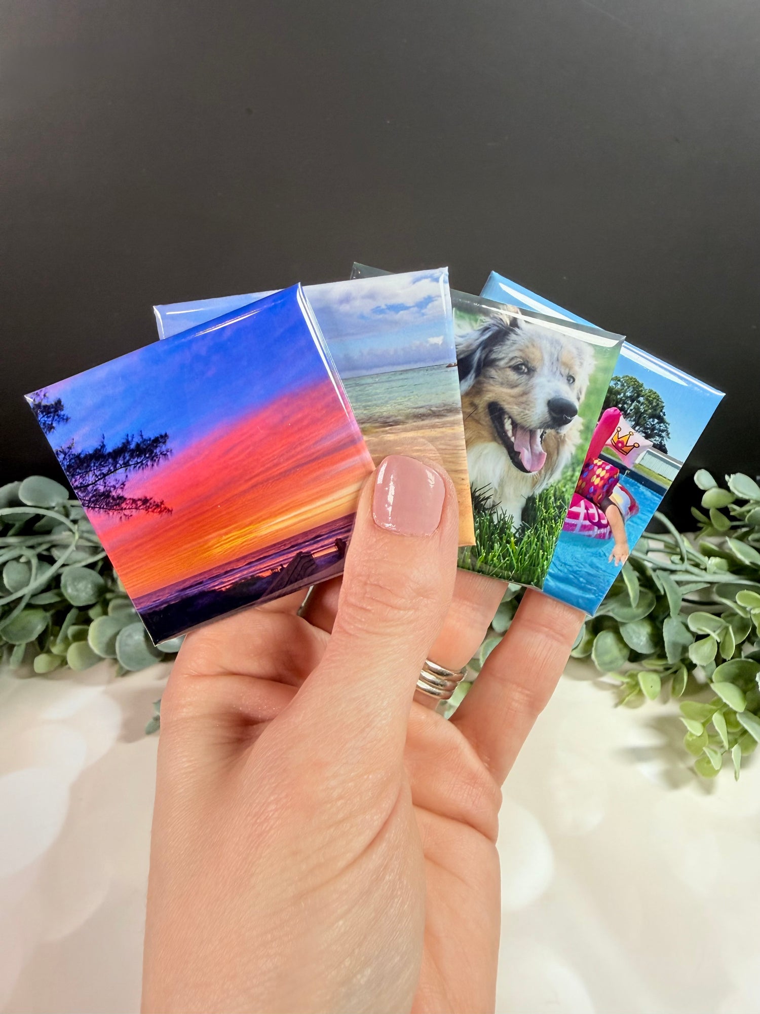 2x2 custom photo magnets with assorted images, held in hand