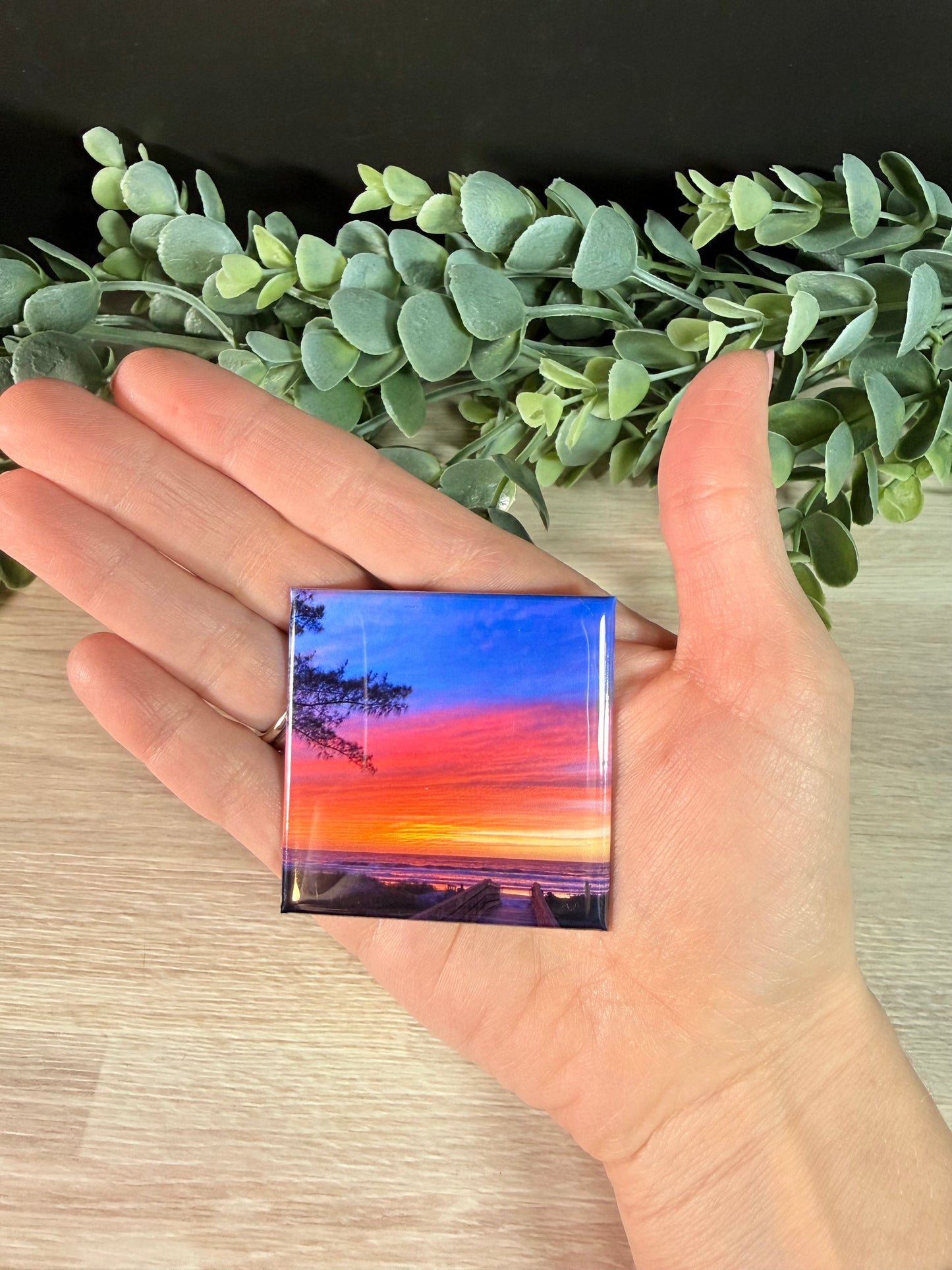 Hand holding 2x2 custom photo magnet with landscape photo