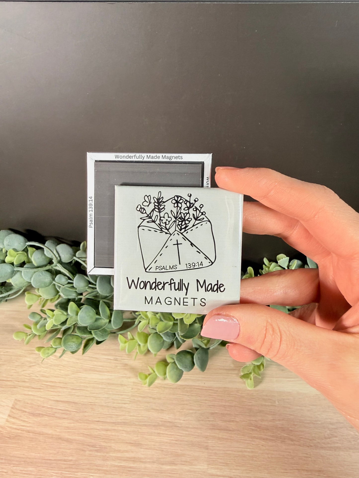 Front and back of 2x2 photo magnet held in hand, featuring Wonderfully Made Magnets logo